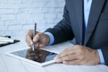a man in a suit writing on a tablet