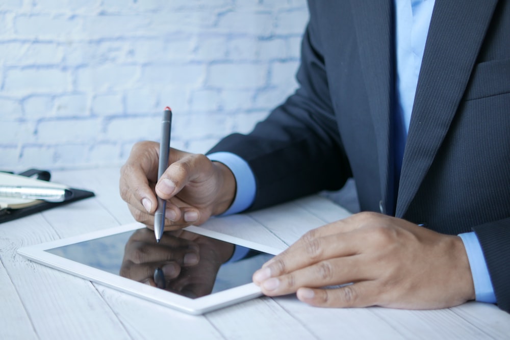 Un homme en costume écrivant sur une tablette