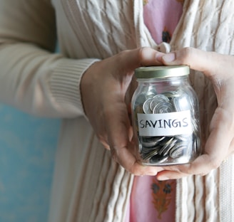 a woman holding a jar with savings written on it