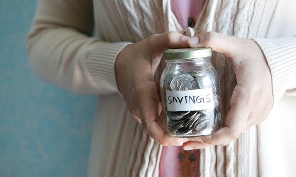 a woman holding a jar with savings written on it