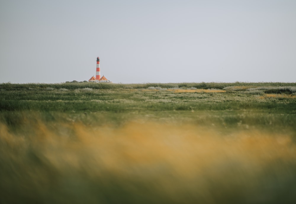 a field with a light house in the distance