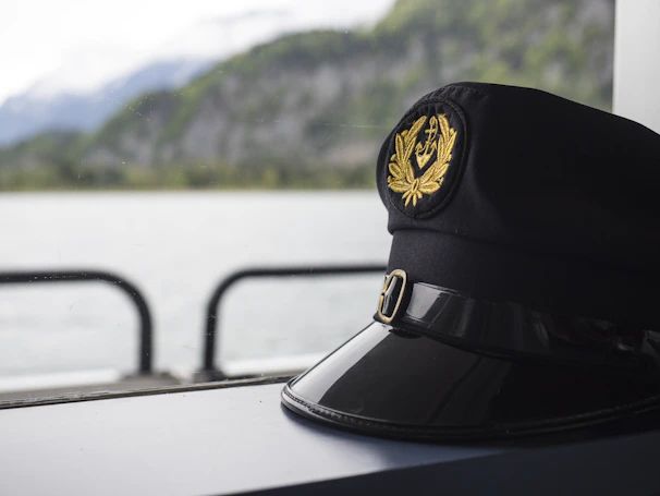 A sleek captain's hat resting on a polished wooden boat deck with a calm sea in the background