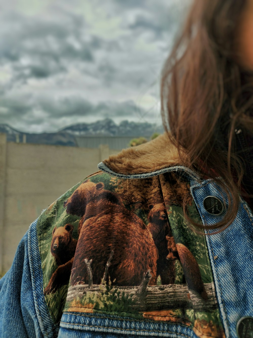 a woman wearing a jean jacket with a picture of bears on it