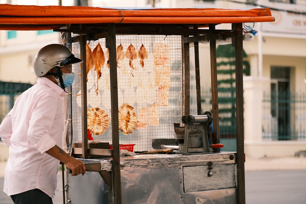 a man wearing a face mask standing next to a food cart