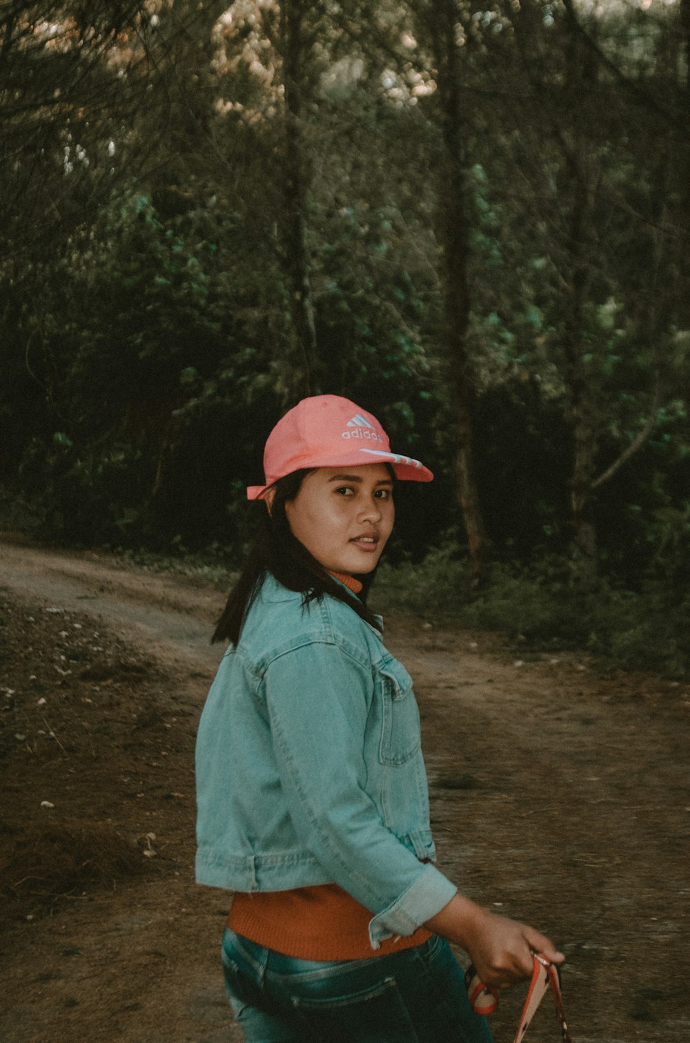 a young girl wearing a pink hat and carrying a skateboard