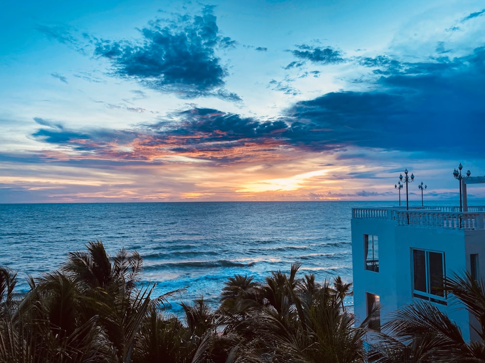 the sun is setting over the ocean with palm trees