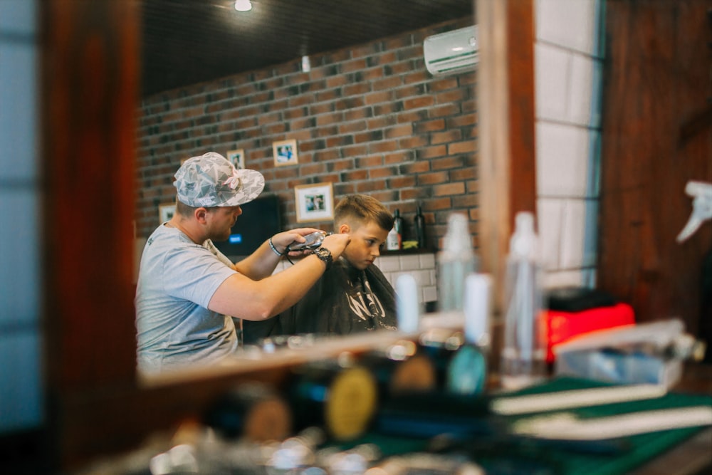 a man cutting a woman's hair in front of a mirror