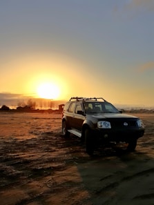 Scenic African landscape with a luxury safari vehicle parked under a golden sunset.