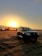 A sleek luxury Land Cruiser parked on a dusty savannah with a dramatic sunset backdrop.