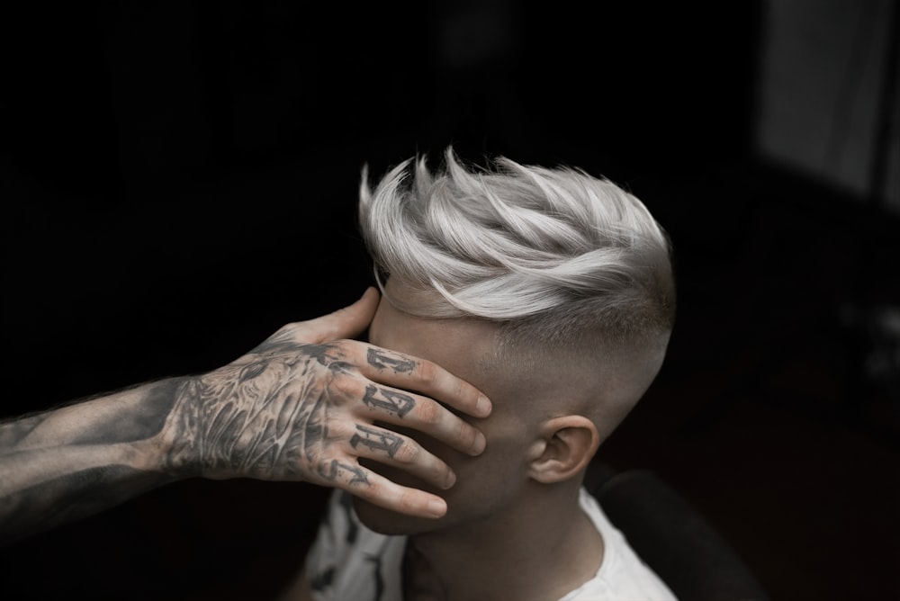 a man with white hair and tattoos covering his face