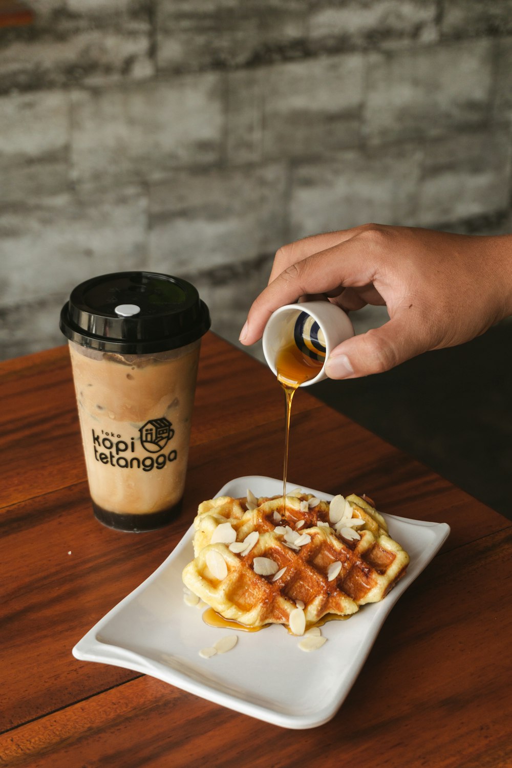 a person pouring syrup on a plate of waffles