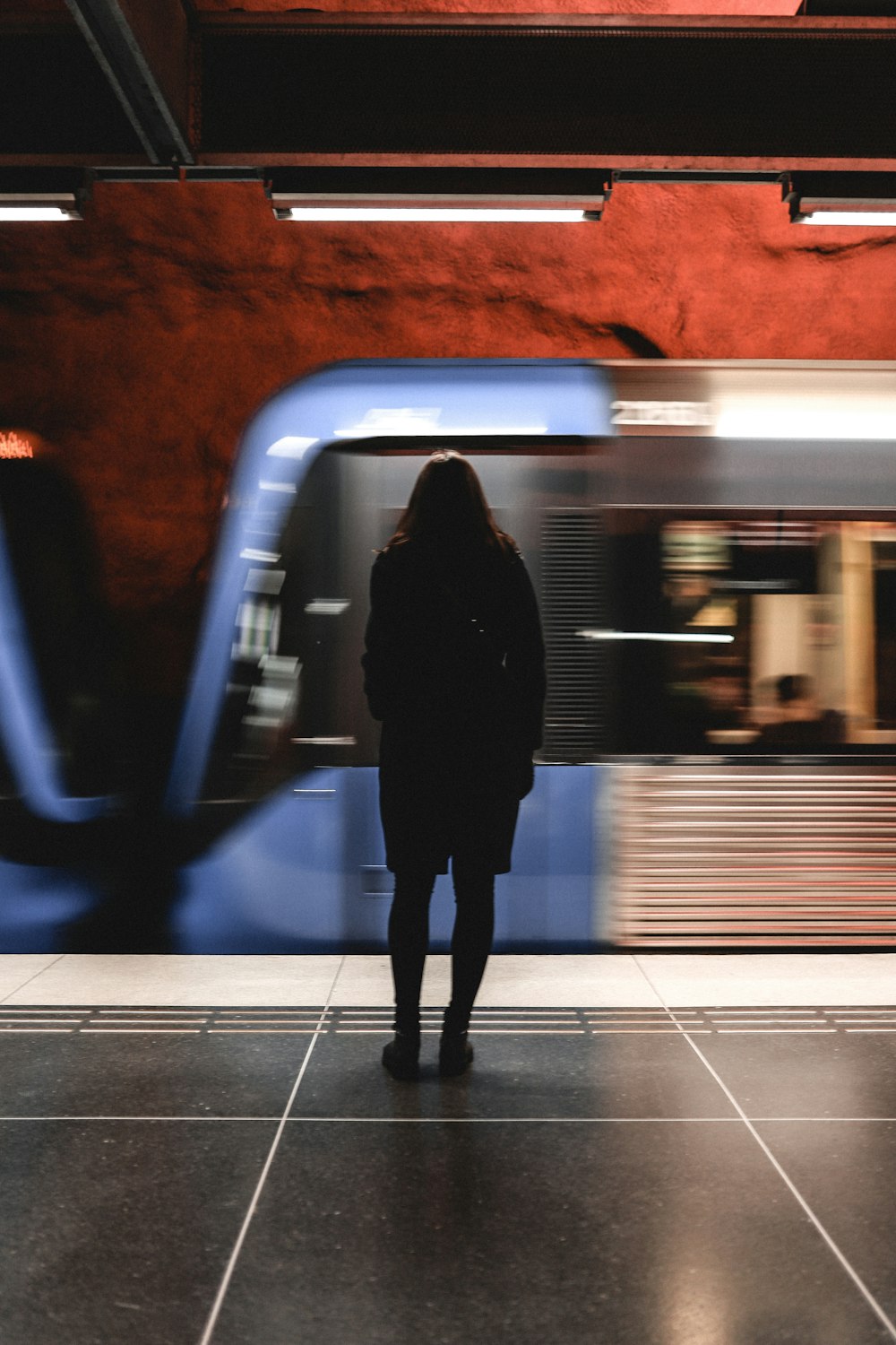 Eine Frau steht vor einem Zug an einem Bahnhof
