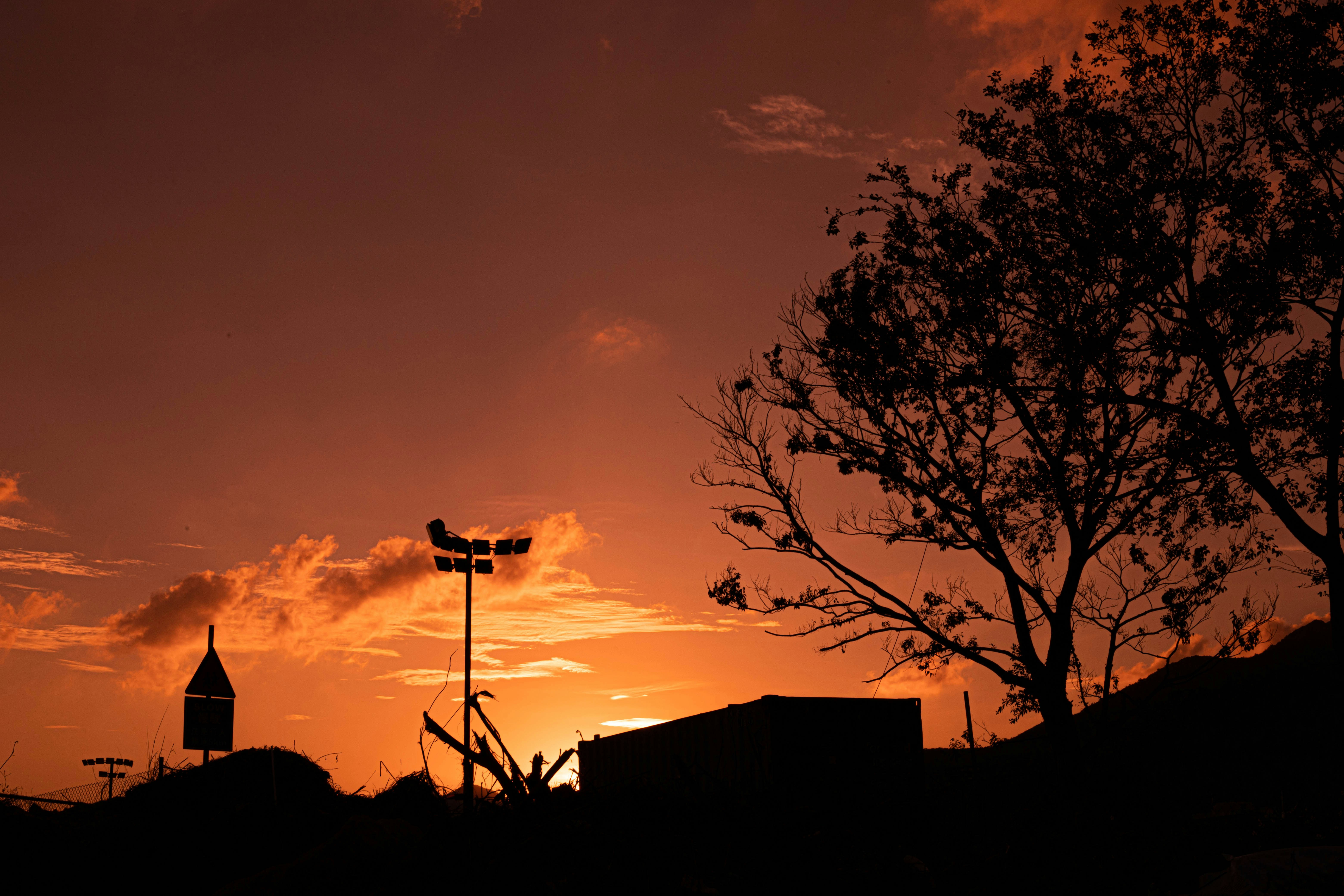 the sun is setting behind a building and a tree