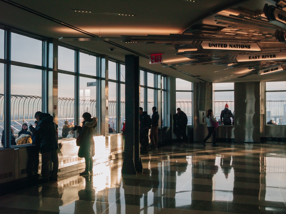 a group of people standing in a lobby next to large windows