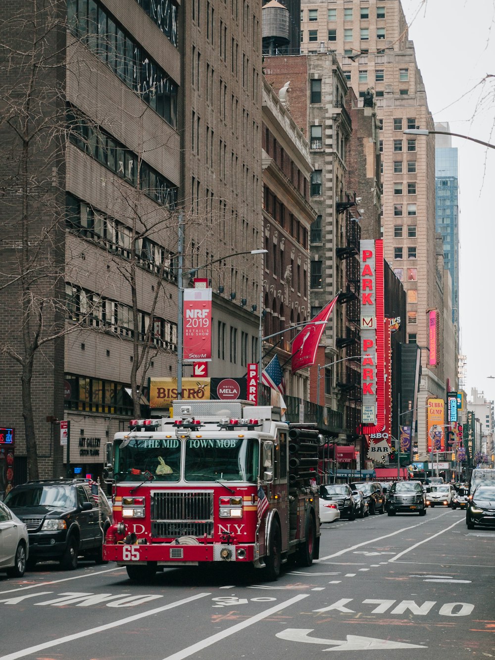a red fire truck driving down a street next to tall buildings