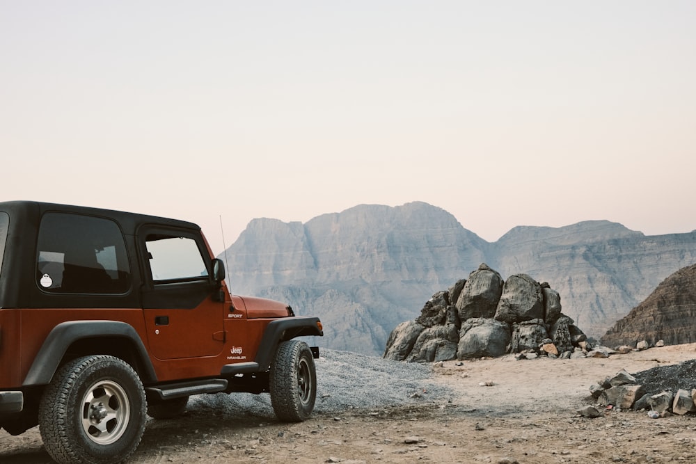 a red jeep is parked in the desert