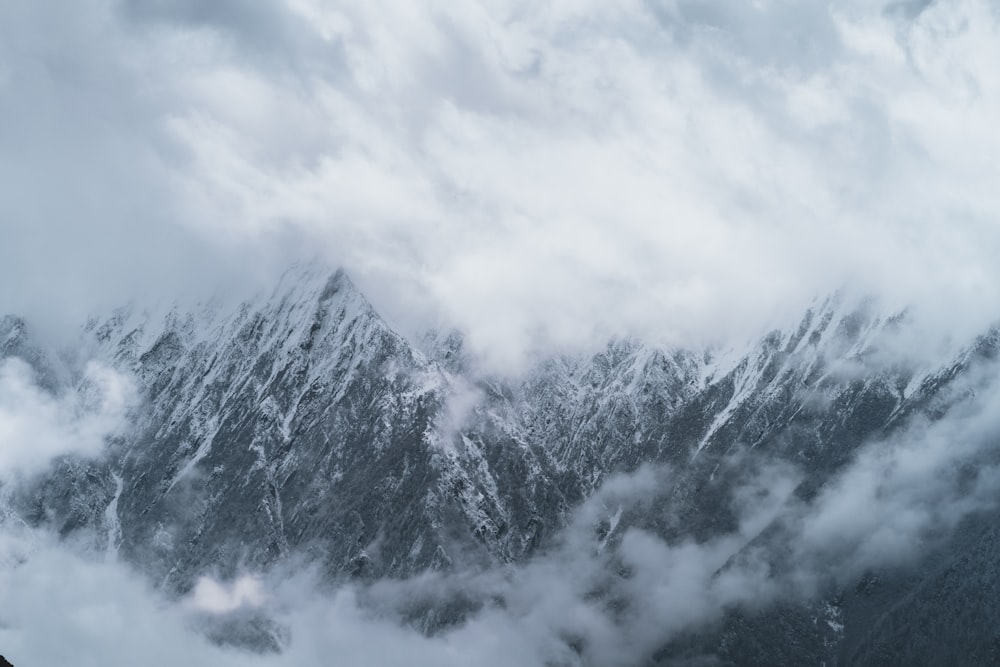 Una montagna coperta di neve e nuvole sotto un cielo nuvoloso