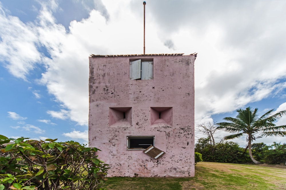 a pink building with two windows and a flag on top of it