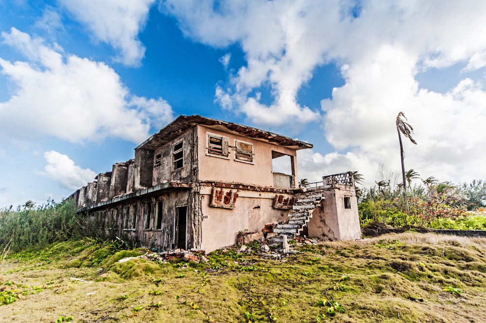 a run down building sitting on top of a lush green hillside