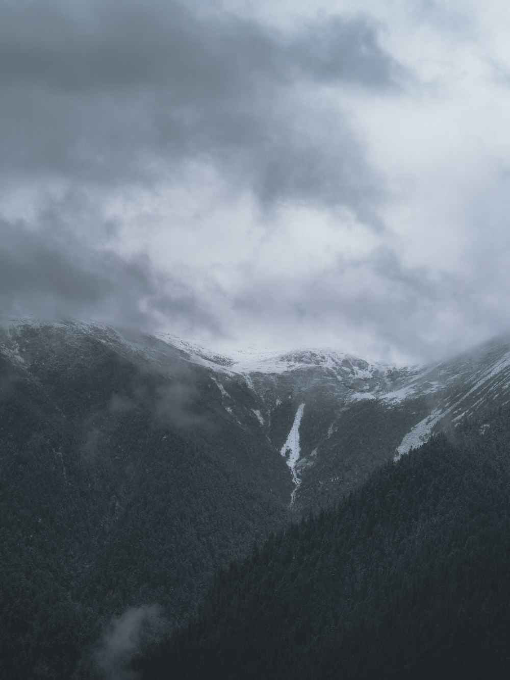 a mountain covered in snow under a cloudy sky