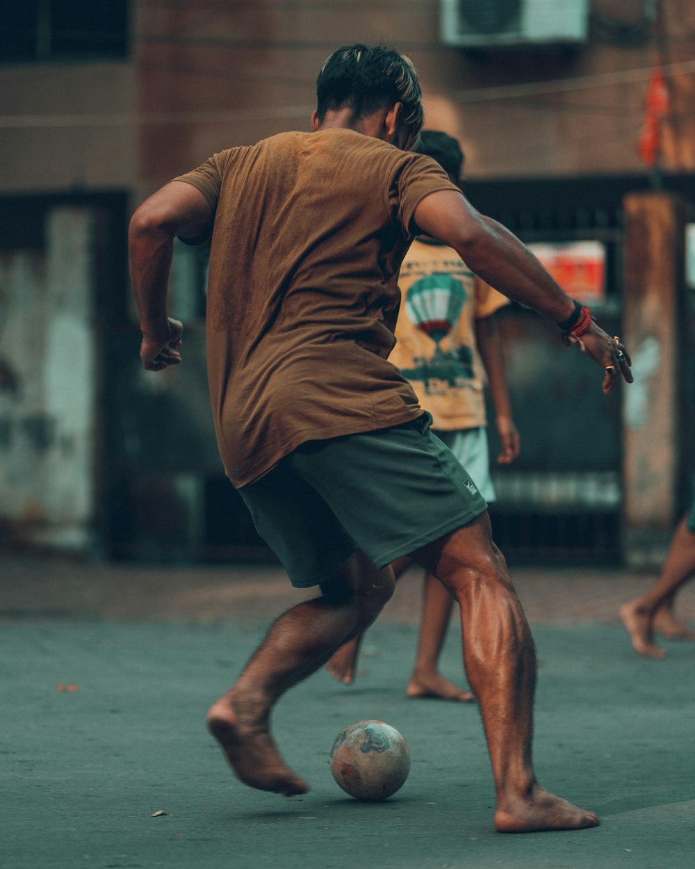 a man kicking a soccer ball on a street