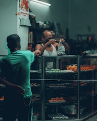 A friendly exchange between a customer and a home baker handing over a box of pastries.