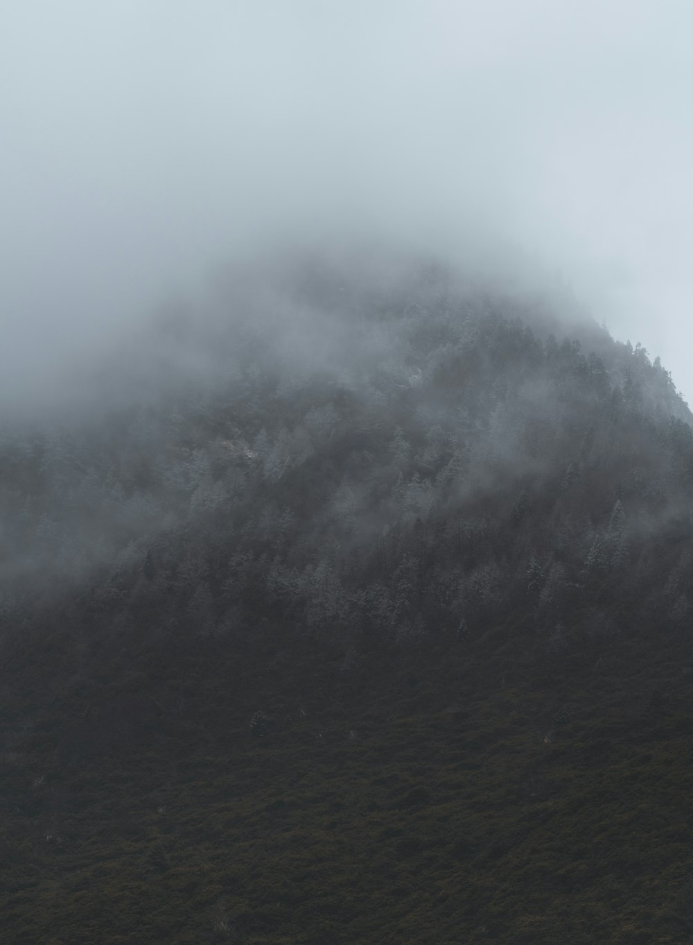 a large mountain covered in fog and clouds