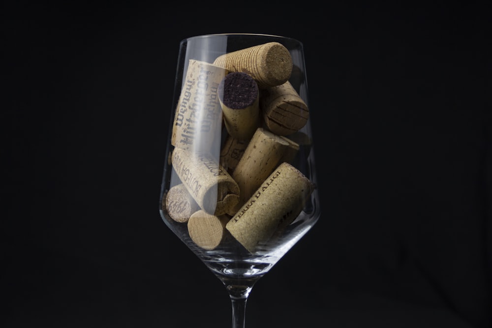 a wine glass filled with wine corks on top of a table