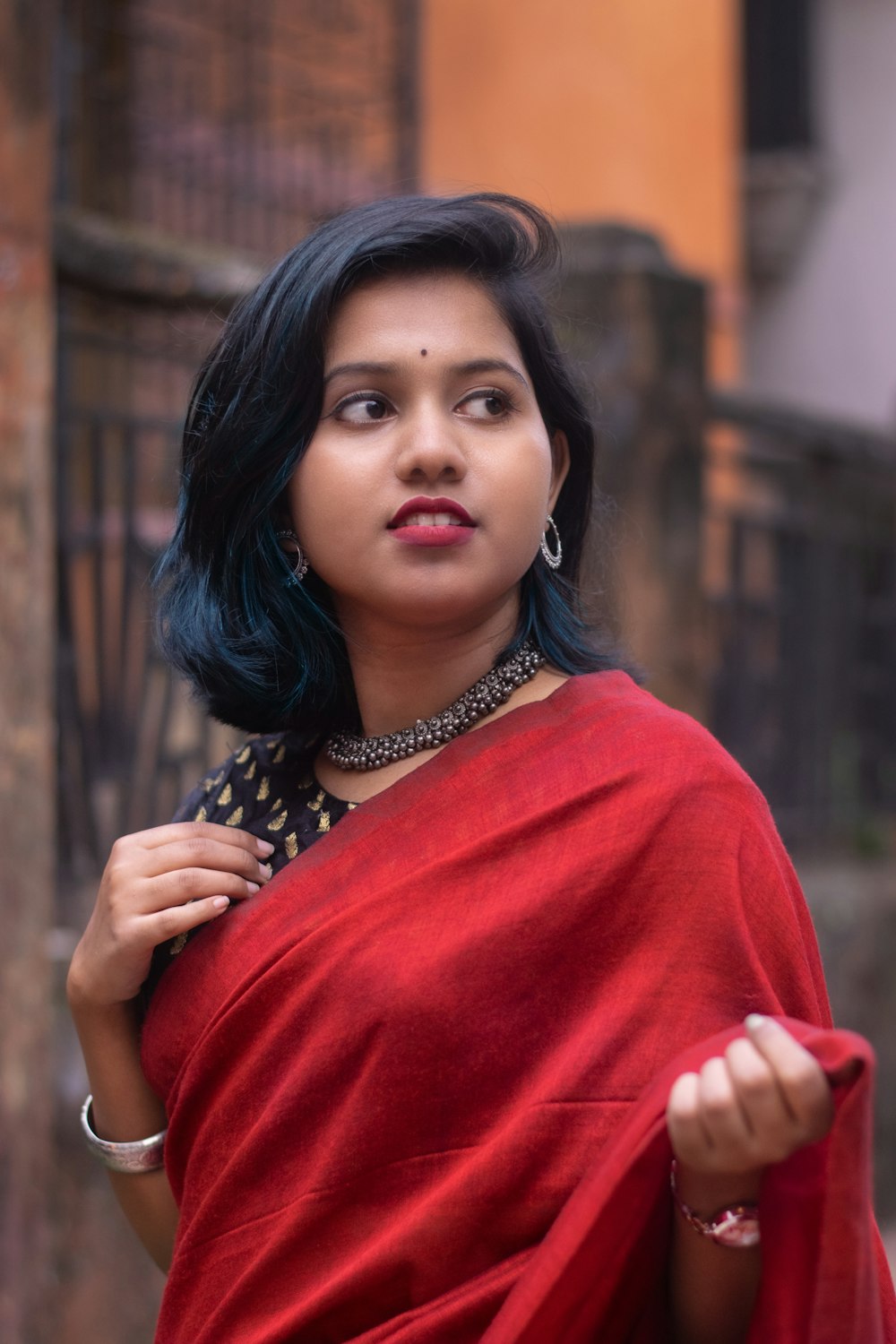 a woman with blue hair wearing a red sari