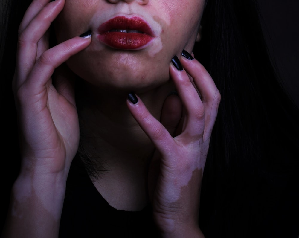 a woman with black nails and red lipstick