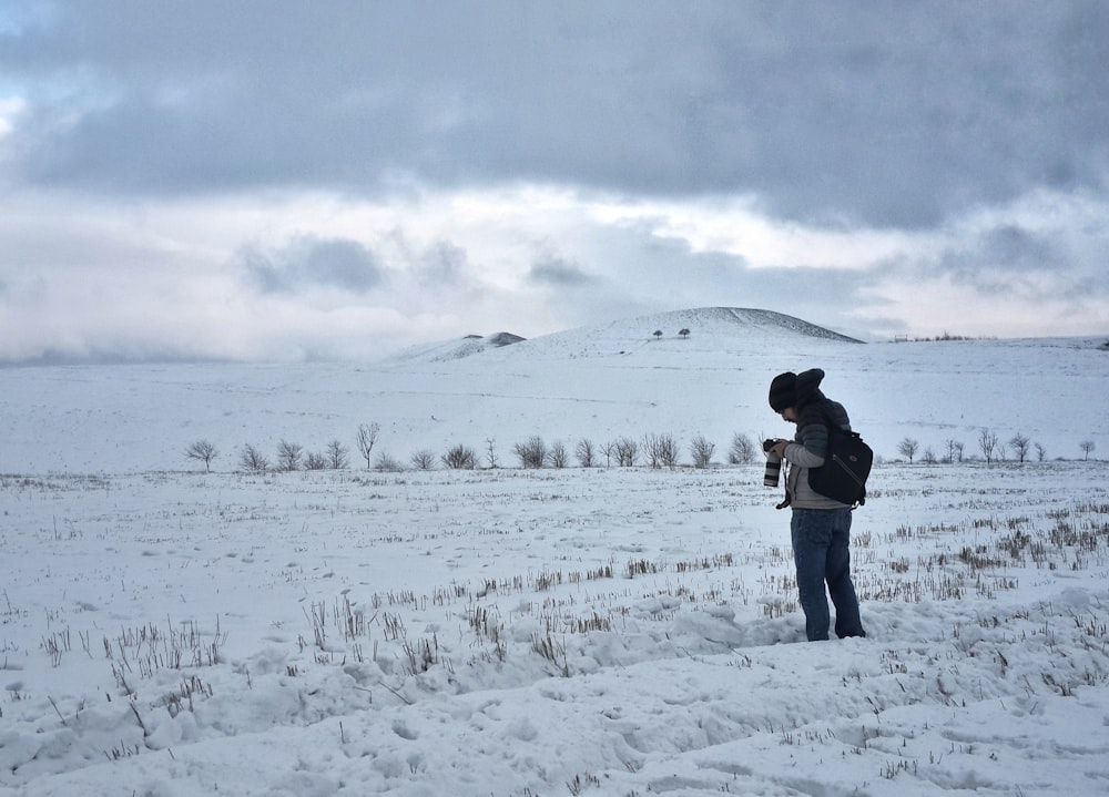 a person standing in the snow with a dog