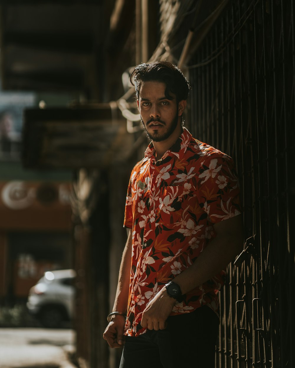 a man standing next to a fence on a street