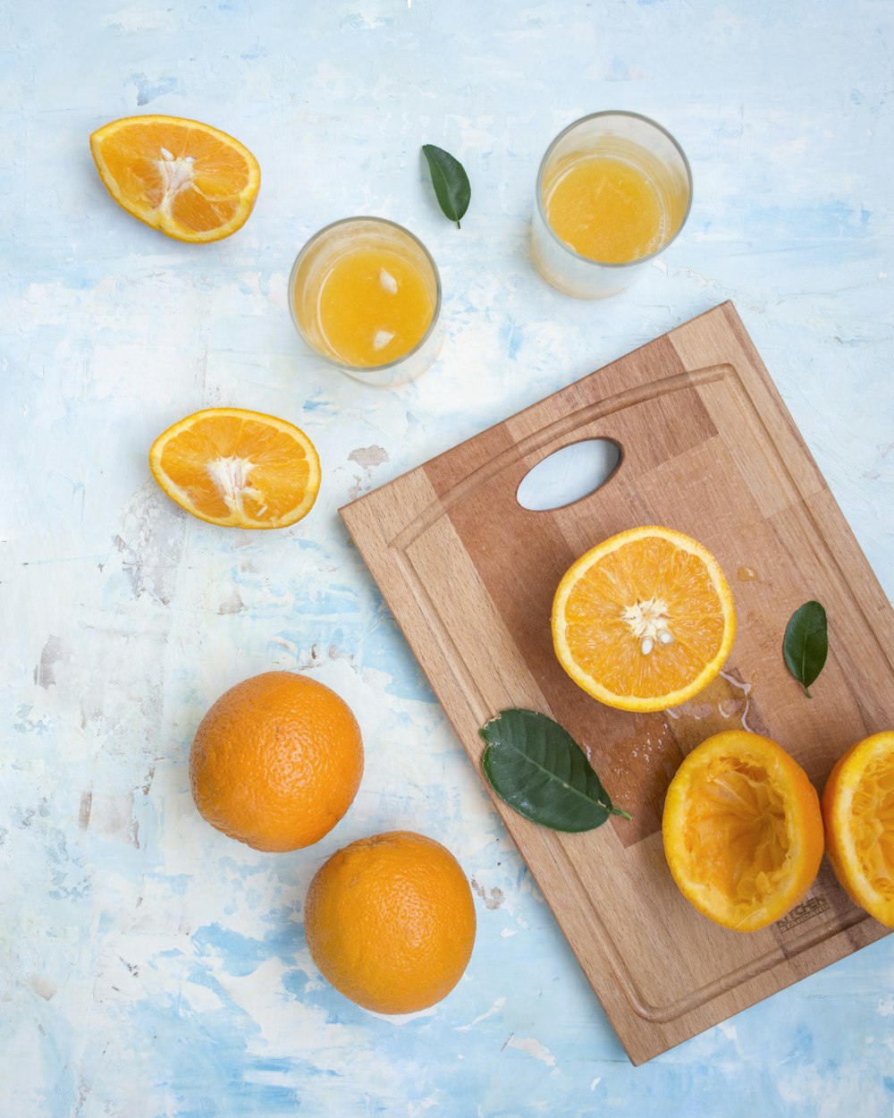 a cutting board topped with sliced oranges next to glasses of orange juice