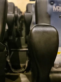 Close-up of luxurious recliner seats with cup holders and plush cushions in a dark-themed private theatre.