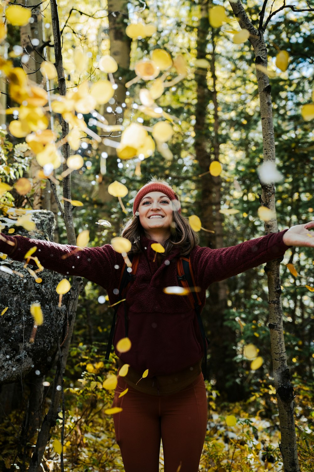 a woman standing in the woods surrounded by falling leaves
