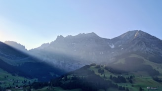 A peaceful Himalayan mountain range glowing softly at dawn behind the retreat.