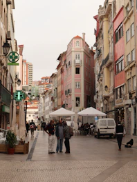 a group of people walking down a street next to tall buildings