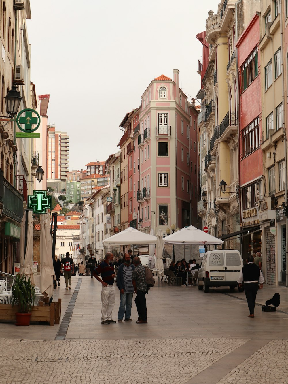 a group of people walking down a street next to tall buildings