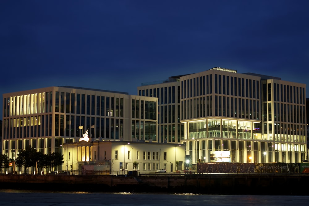 a large building lit up at night by a body of water