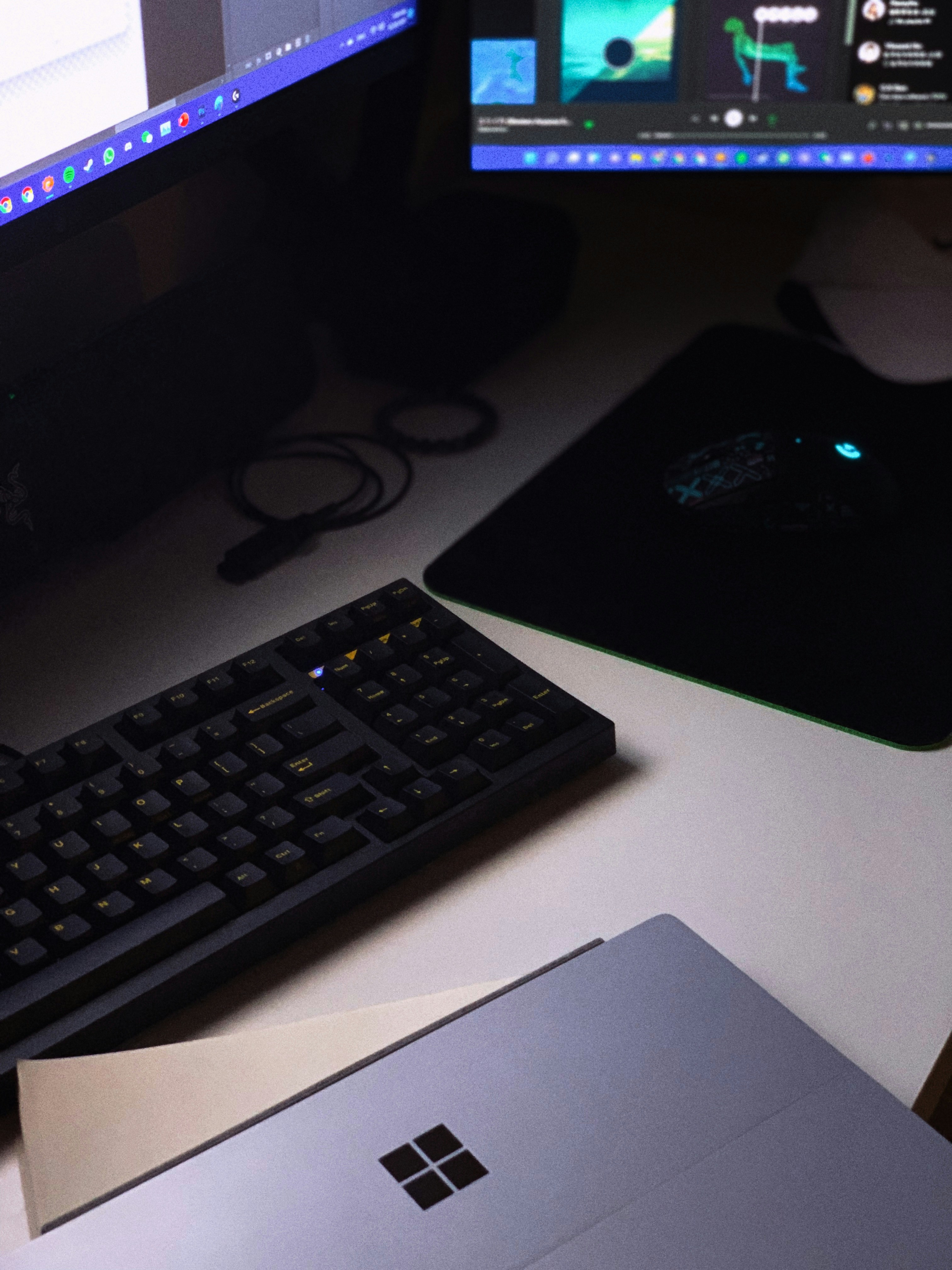 Dark home office setup with glowing laptop screen in dim room, dramatic side lighting