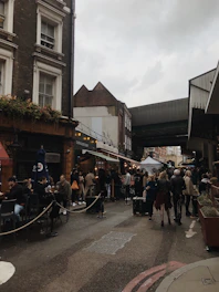 A lively city street scene with people enjoying coffee and dining outdoors under string lights.