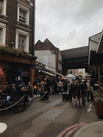 A lively city street scene with people enjoying coffee and dining outdoors under string lights.