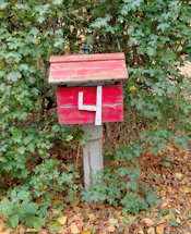 A rustic wooden mailbox with fresh farm flowers beside it, set against a backdrop of the Klamath River valley.