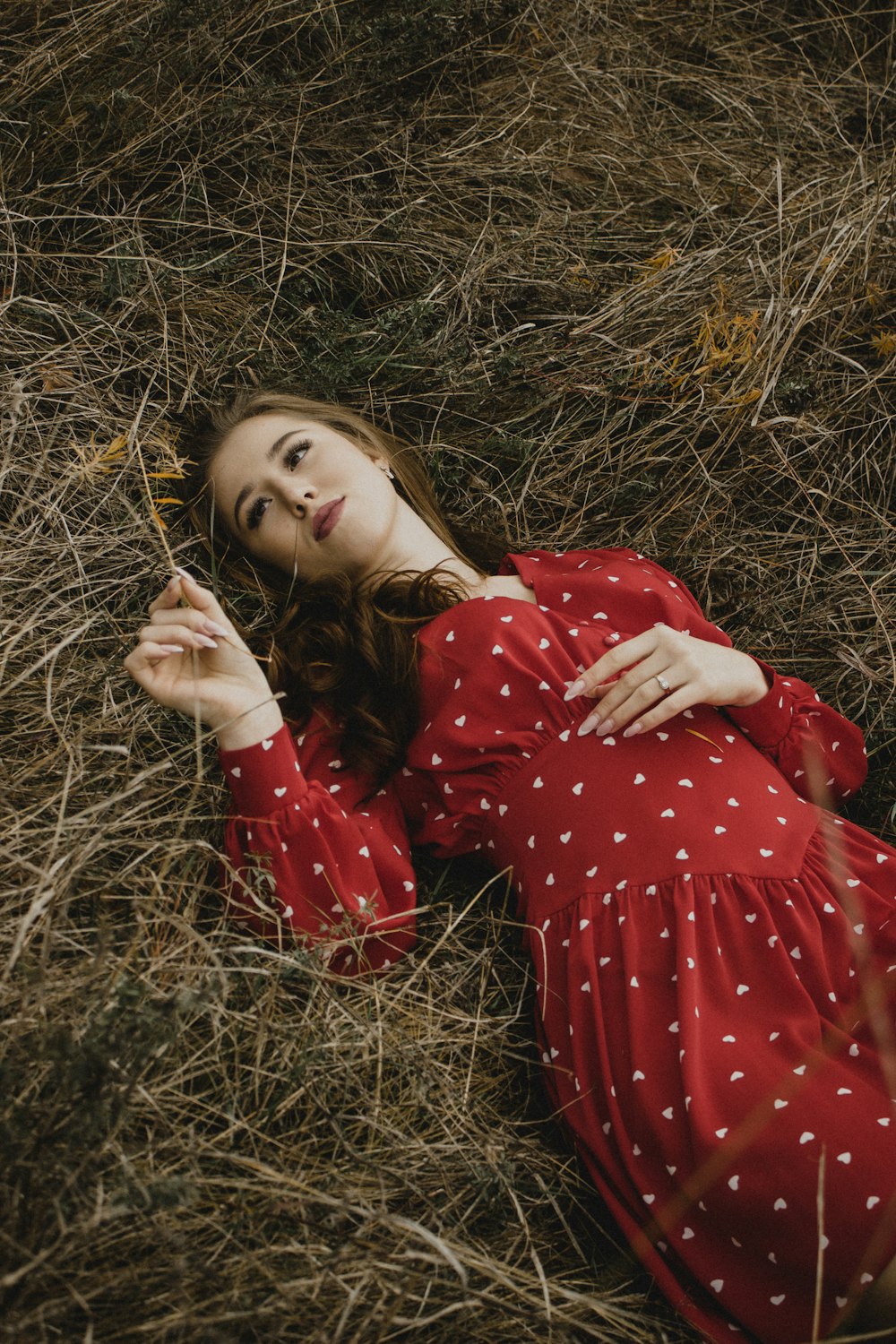 a woman in a red dress laying on the ground