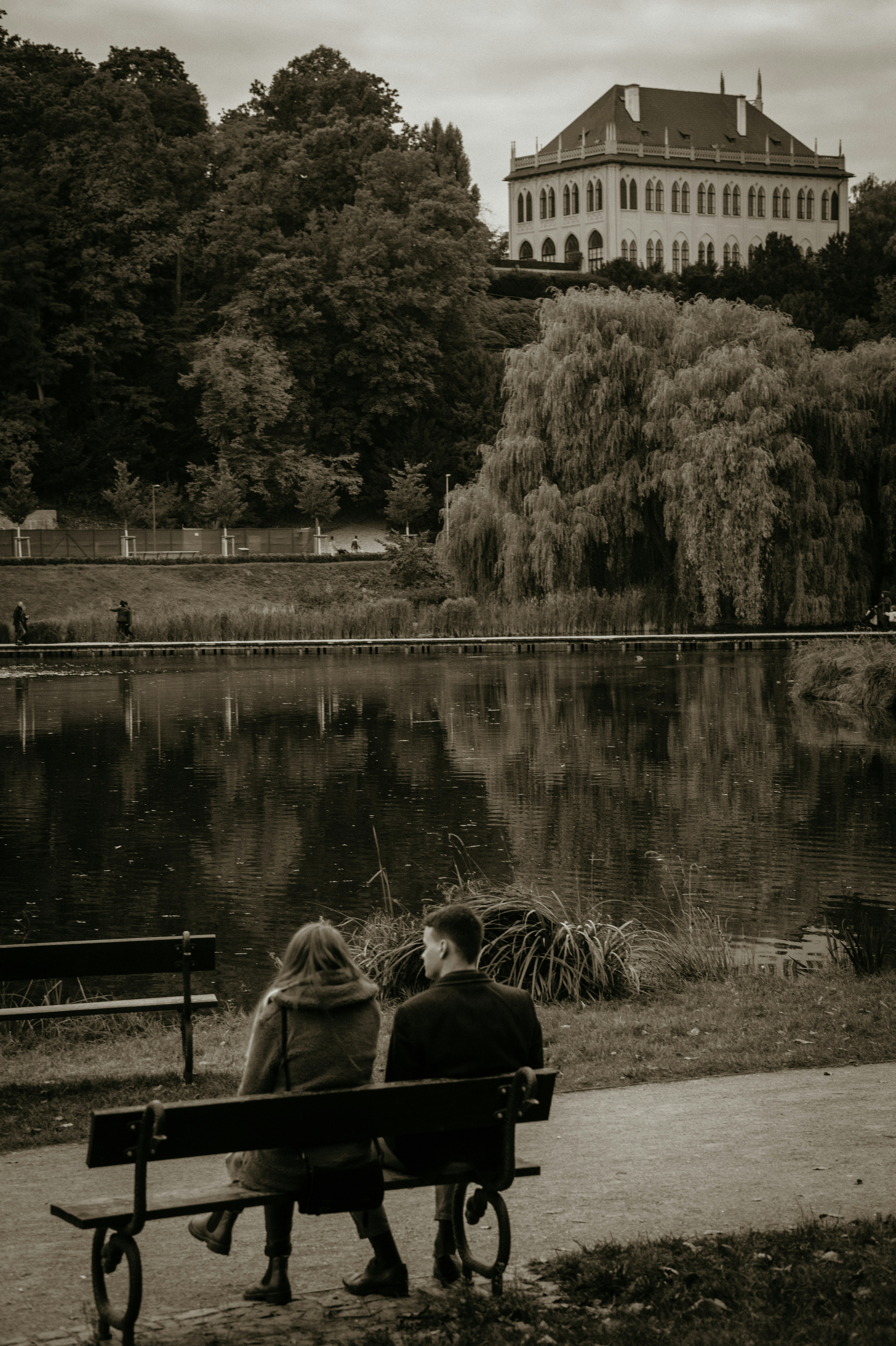 two people sitting on a bench near a lake