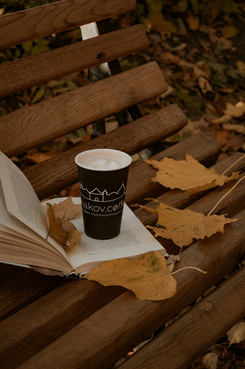 an open book and a cup of coffee on a bench