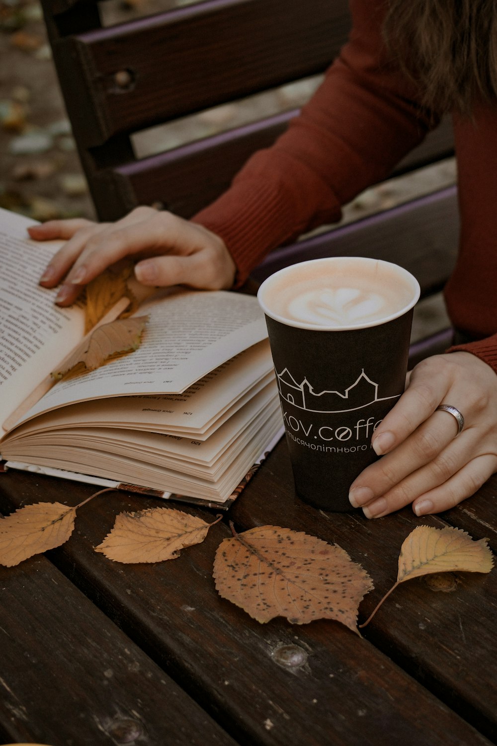 une personne assise à une table avec un livre et une tasse de café