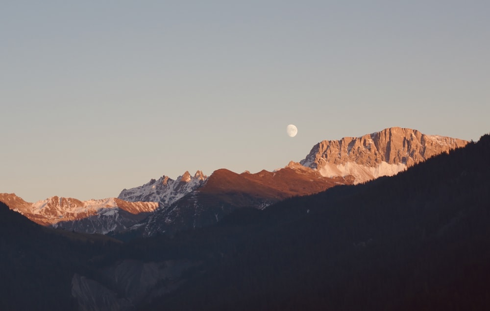 uma vista de uma cordilheira com uma meia-lua no céu