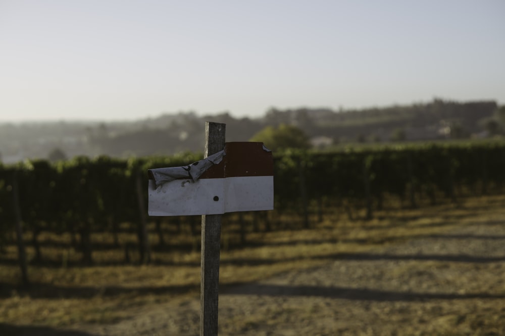 a red and white sign sitting in the middle of a field