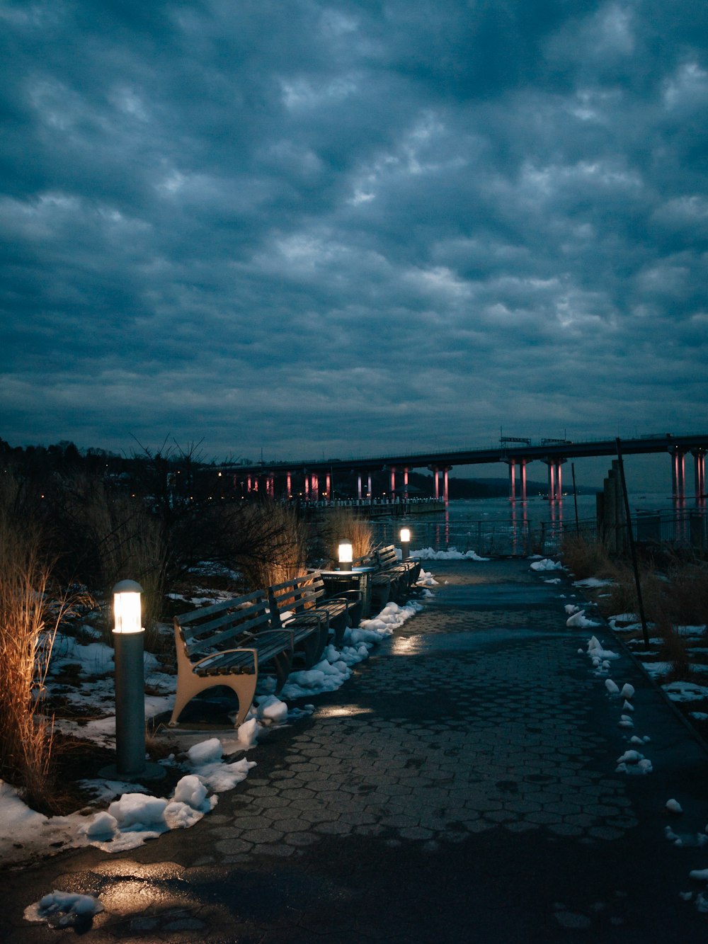 a walkway with snow on the ground and lights on